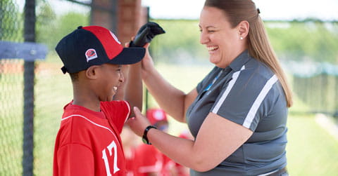 An athletic trainer examines the shoulder of a baseball player.